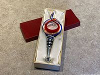 stopper seated in satin-lined box, red lid beside