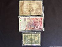 Front view of three banknotes in protective sleeves: Spain 100 Pesetas 1953 (top), France 200 Francs 1997 (middle), Italy 50 Lire (bottom)