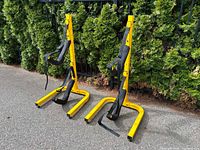 Front view of both yellow freestanding racks showing padded cradle arms and straps