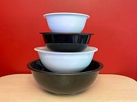 Four Pyrex bowls stacked to show alternating black and white colours and nesting sizes