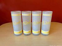 Front view of four frosted McDonald’s glasses showing logos and stripe design