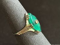 Side view of ring showing marquise green stone, gold split shoulders