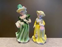 Front view of both porcelain lady figurines showing colours, poses and scale
