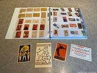 Binder open showing clear pages with assorted labels and wrappers plus loose advertising cards