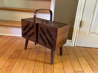 closed wooden cantilever sewing box on legs with handle