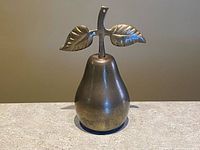 Front view of solid brass pear-shaped hand bell showing overall form and patina