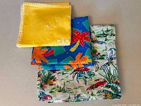 Stacked view of three folded linens showing prints and embroidery