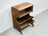 Full front view of wooden magazine rack and telephone stand showing shelves, carved sides, and condition