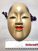 Front view of mask-shaped porcelain decanter with ruler for scale