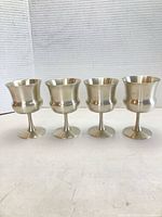 Full view of four pewter goblets standing side by side