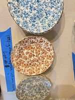 Three chintz pattern saucers in blue, rust and gray showing tops and gold gilt scalloped rims