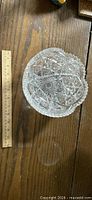 Top view of deep cut glass bowl showing starburst and scalloped rim beside ruler