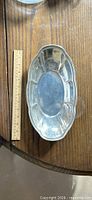 oval silver-plated serving dish beside ruler