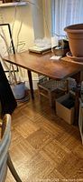Side view with one leaf raised showing rectangular top, warm brown finish, surrounding items not included
