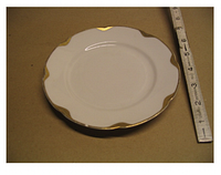 Bread & butter plate with scalloped gold rim beside ruler