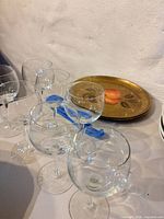 six clear balloon goblets grouped with gold painted plate behind