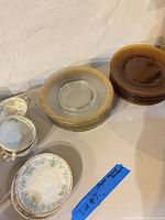 Amber plates, clear gilt-rim plates, porcelain teacups and saucers grouped on table