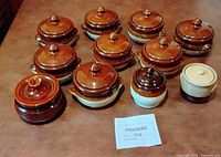 Group of eleven lidded stoneware ramekins on countertop