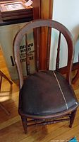 Wood spindle-back chair with torn dark vinyl seat
