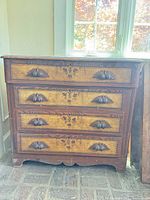 Front view showing four drawers, inlay, carved hardware