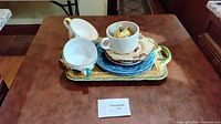 overview of stacked plates, bowls, creamer, honey pot on serving tray
