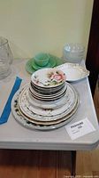 Stacked assortment of plates and bowls showing variety of sizes and floral/gold patterns