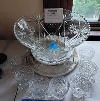 punch bowl resting on surface with cups arranged, shows pattern and count