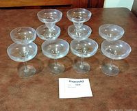 Group of nine clear champagne coupes lined on tabletop