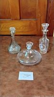 Group shot of three clear glass decanters with stoppers
