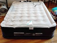 Inflated twin air mattress showing white top, black sides, built-in cord and pump panel