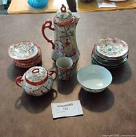 Group shot of entire porcelain set showing pot, sugar bowl, cup, bowl, two stacks of plates