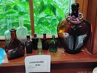 All eight glass bottles and demijohn on windowsill