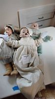 Front view of three antique/vintage dolls on table showing clothing and overall condition