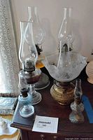 Group shot showing five lamps including brass banquet lamp, blue miniature lamp and clear glass examples