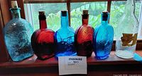 Group shot of six glass bottles on windowsill showing colors and sizes