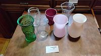 Group shot of seven assorted glass vases showing colors, shapes and sizes