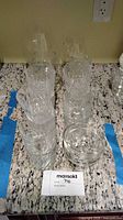 Group of stacked tumblers, small bowls and additional glass pieces on countertop