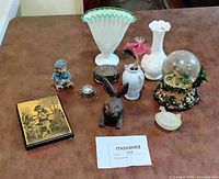 All items arranged on table showing variety of vases, figurines, snow globe, trinket boxes and decorative pieces