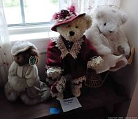 All three dressed collectible teddy bears on bench under window