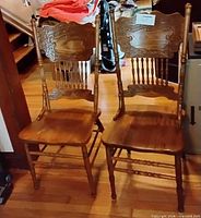 two of the dining chairs front view showing turned spindle backs and wooden seats