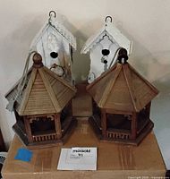 Two white distressed house-style birdhouses and two natural brown gazebo birdhouses grouped together