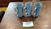 Six light blue mugs stacked in two columns