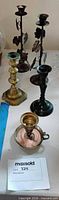 Group of six assorted candlesticks showing relative sizes and finishes