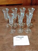 Seven of the clear glass cordial glasses shown standing on table