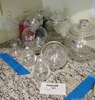 Group shot of all glass apothecary jars with lids on countertop
