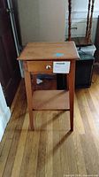 Front view showing drawer with round knob, top surface and lower shelf