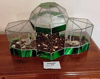 front view of stained glass terrarium showing three connected sections and soil inside