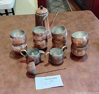 Full set arranged on table: pot, creamer, sugar bowl, six cups, ladle, stirrer