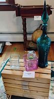 All six items grouped: teal decanter, clear cube vase, pink cube vase, one globe terrarium visible, wooden crate base
