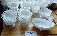 Group of white milk glass compotes, bowl, square dish and goblet on tabletop